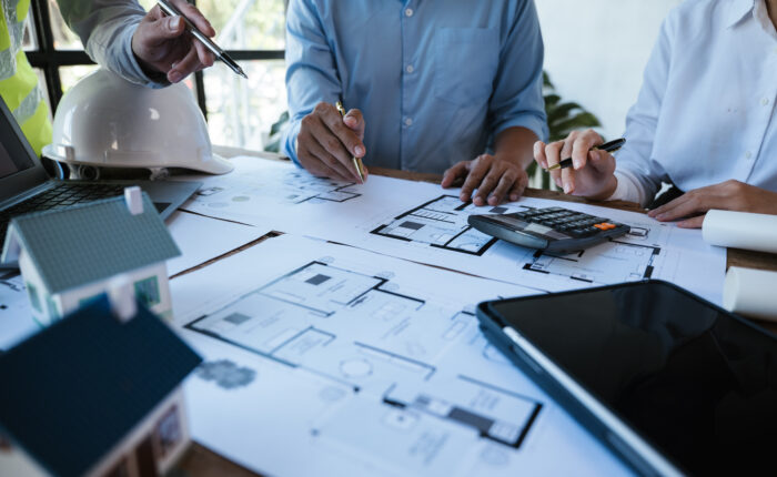 Close up of hands working calculate and brainstorming on paperworks and floor plan drawings about design architectural and engineering for houses and buildings.