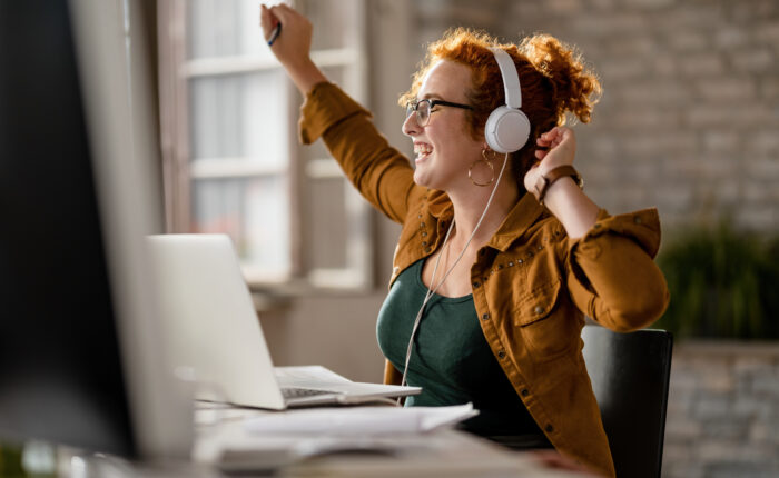 Casual businesswoman having fun while listening music at work.