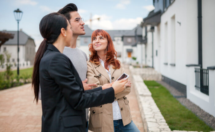 Young couple with real estate agent visiting house for sale in r