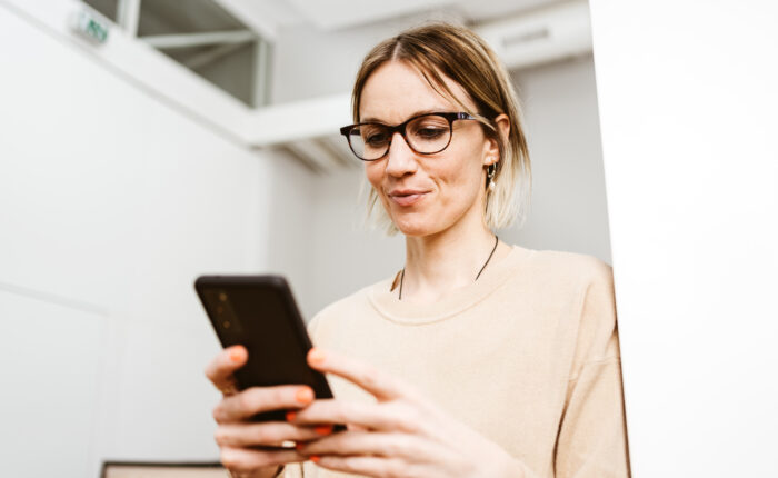 Young business woman with glasses looking at her cell phone