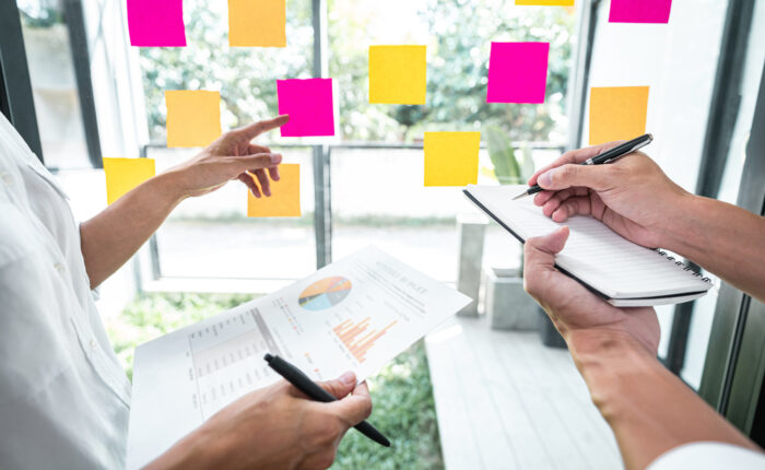 Young creative team professional using post it notes in glass wa